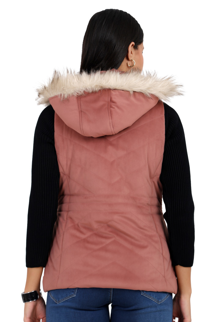 A back pose of a standing woman, wearing Coatsnmore’s half sleeves jacket in onion pink colour with a textured pattern, removable hood with faux fur trim, and blue jeans.